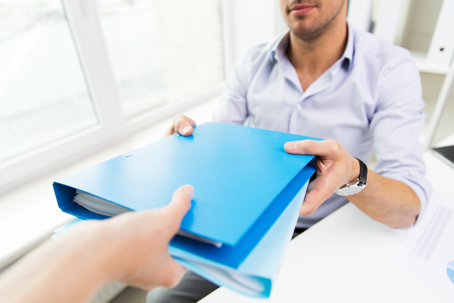 close up of businessman taking folders with papers from secretary hand in office